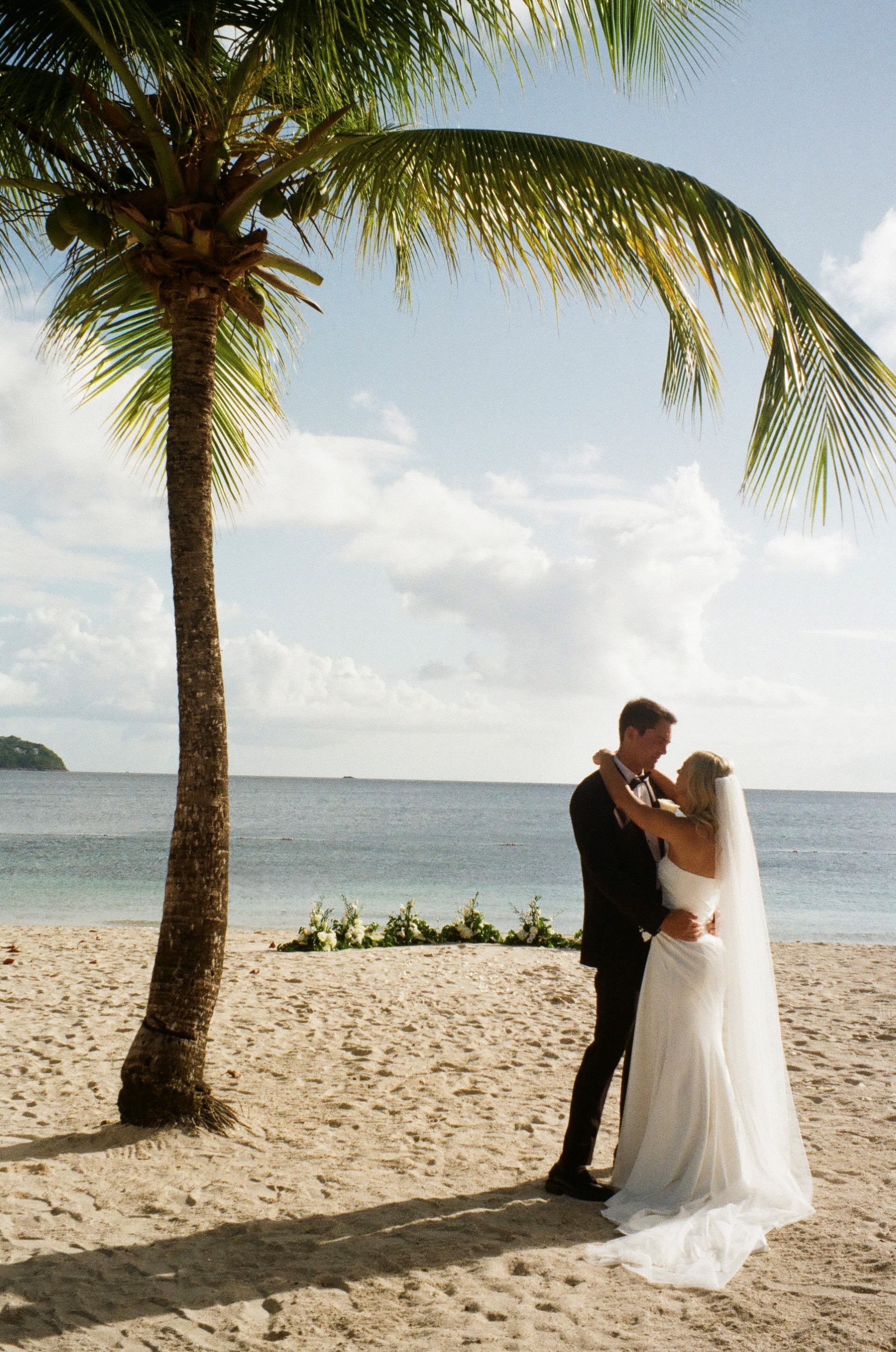 bride and groom embracing on a palm-lined beach in Saint. Lucia