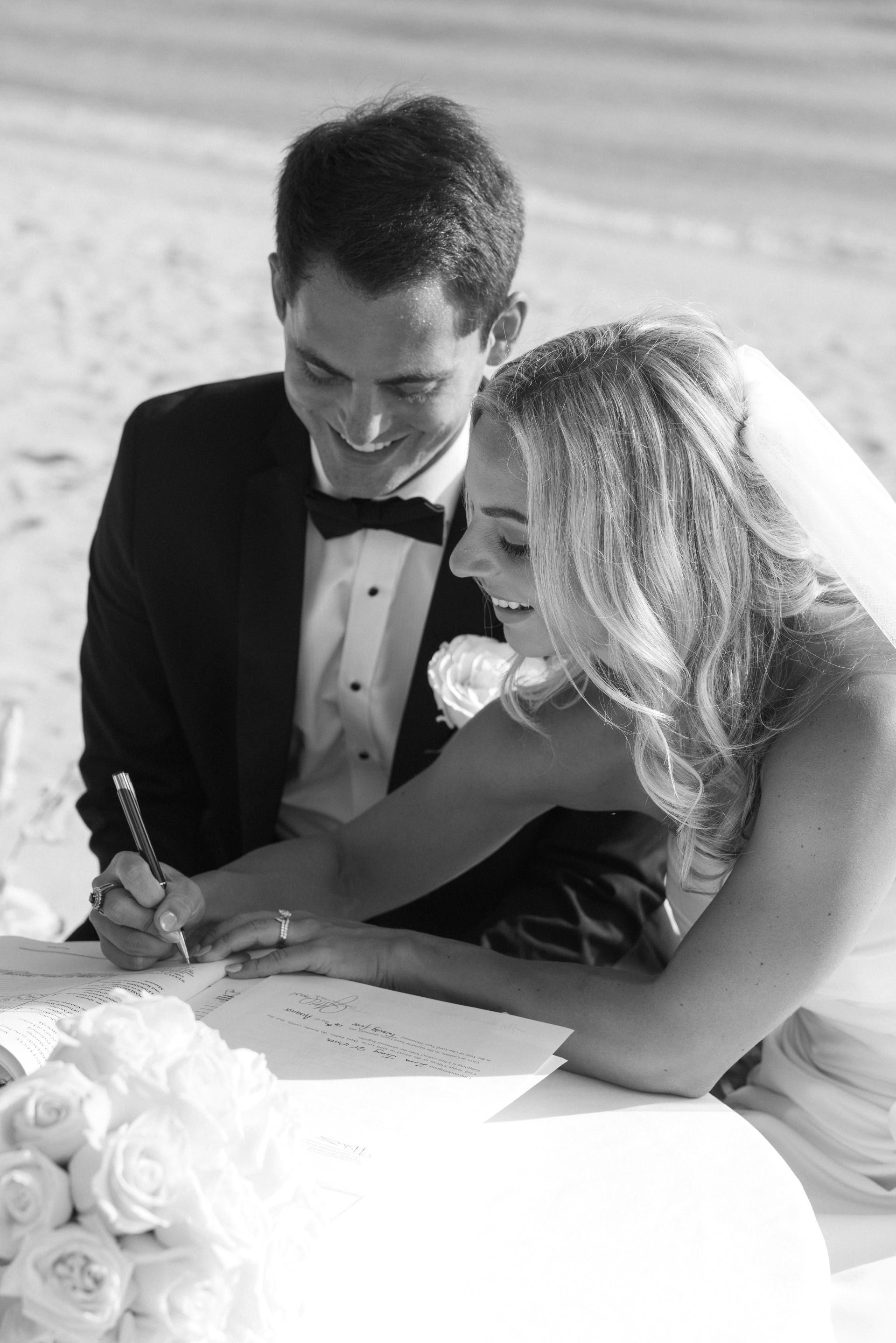 bride and groom signing their marriage license during a beach elopement